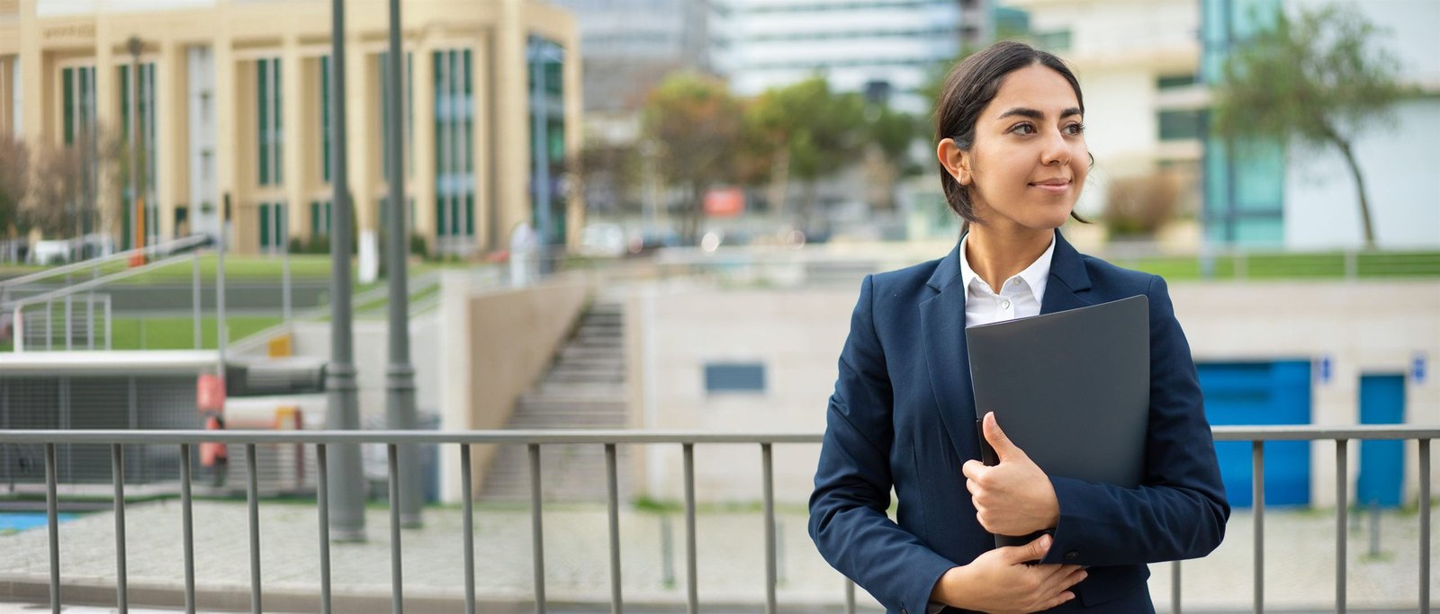 An automation professional holding a project folder outside an industrial campus
